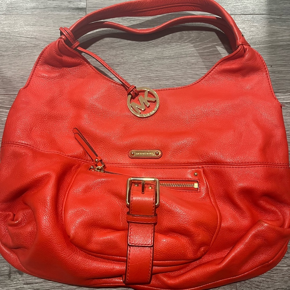 Michael Kors orange purse with gold hardware.